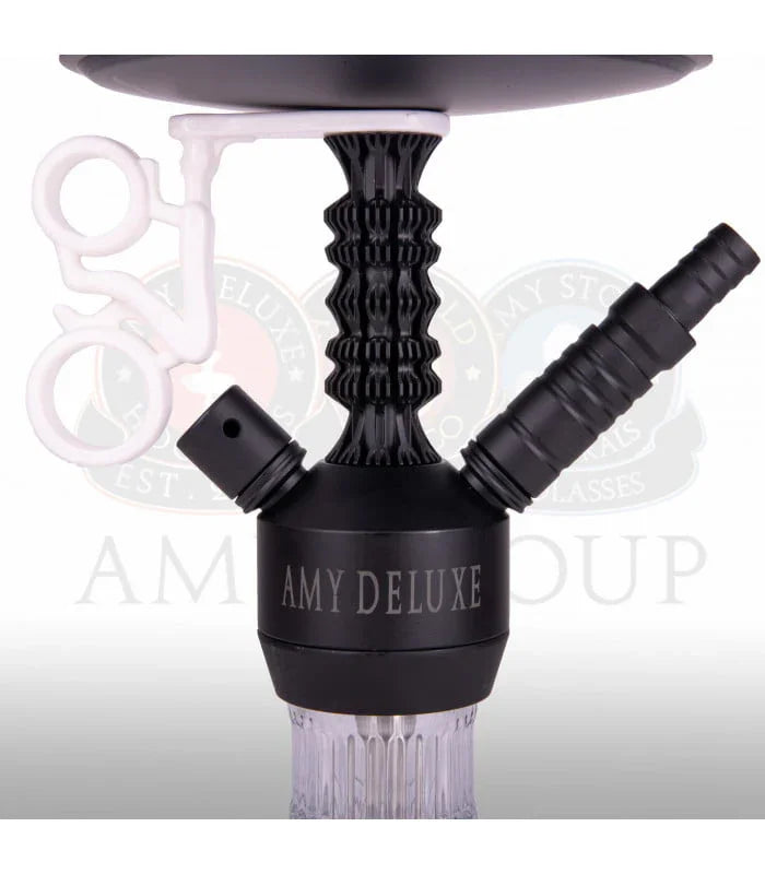 Detail of a black aluminium stem with the hose connection and a closing cap beside it, with the silicone tongs holder on the plate.